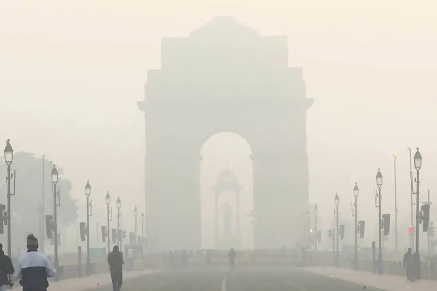 Vehicles commute through the India Gate area covered with smog